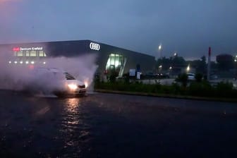 Ein Auto fährt durch eine überflutete Straße: In NRW hat es heftige Regenfälle gegeben.