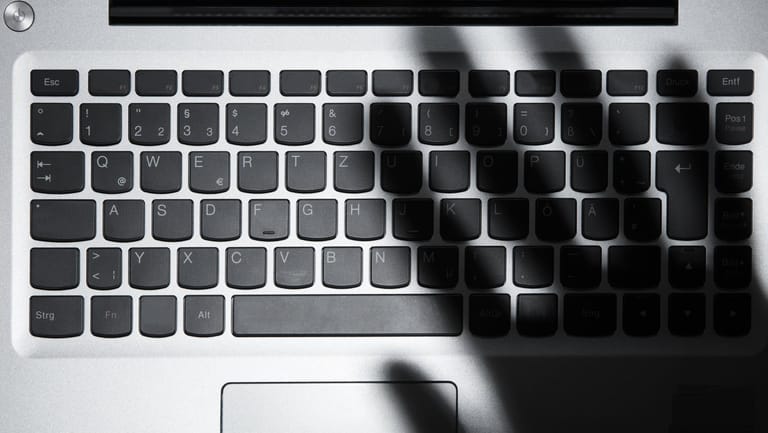 Schatten einer Hand über einer Tastatur (Symbolbild): In NRW wurden mehrere mutmaßliche Internet-Betrüger gefasst.