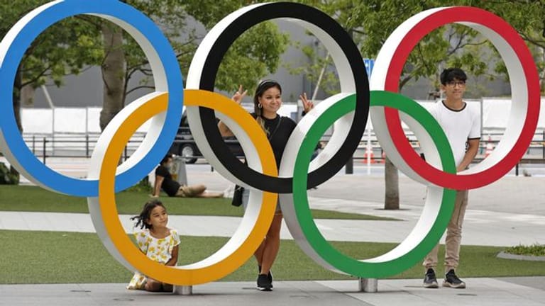 Menschen stehen hinter den Olympischen Ringen