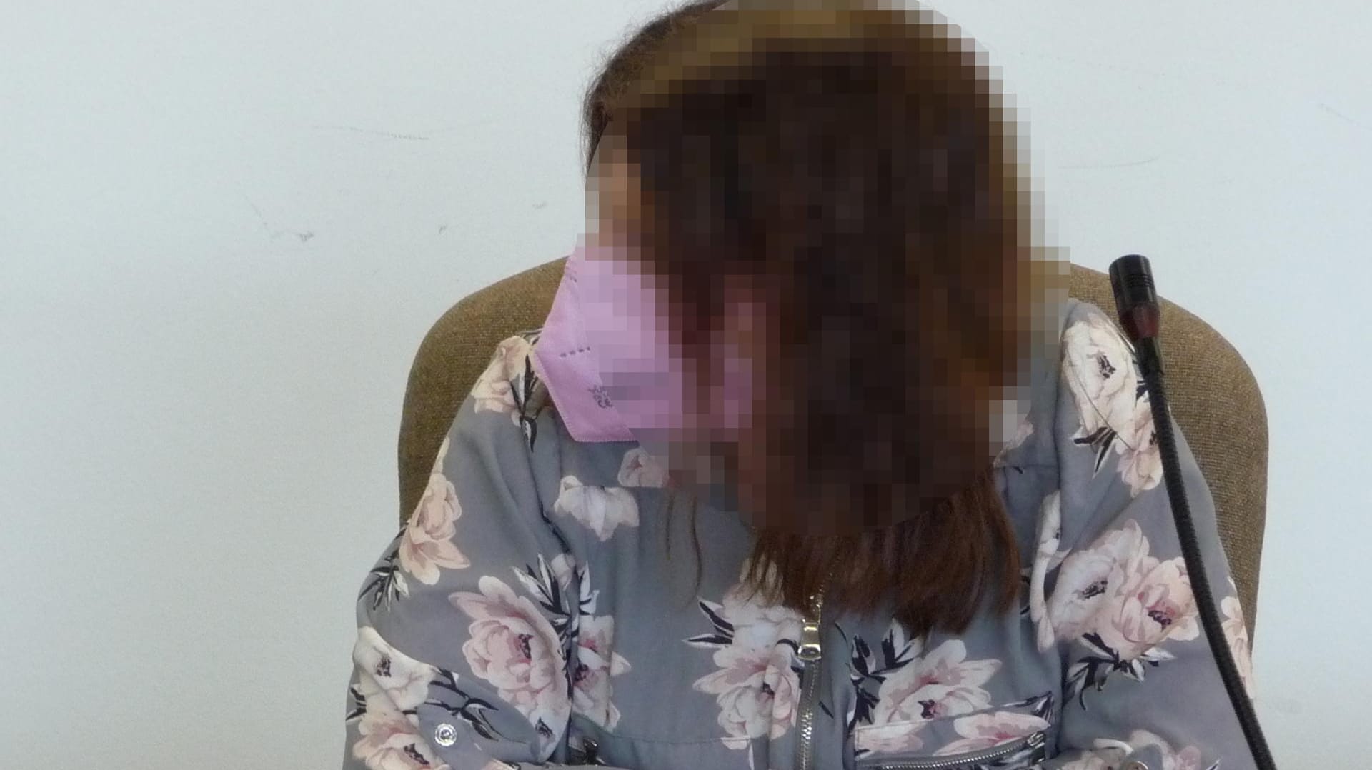 Die Mitangeklagte vor Gericht: Sie erschien mit einer rosafarbenen Maske und in einer Bluse mit rosa Blüten.