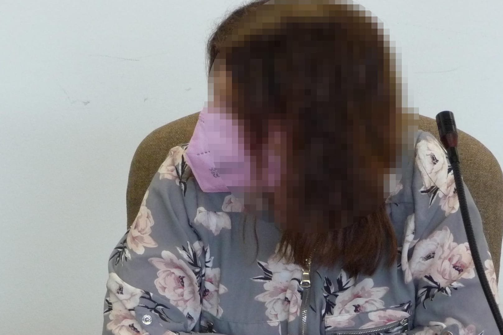 Die Mitangeklagte vor Gericht: Sie erschien mit einer rosafarbenen Maske und in einer Bluse mit rosa Blüten.