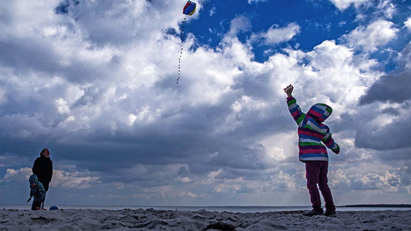 Eine Urlauberfamilie lässt am Strand von Boltenhagen (Mecklenburg-Vorpommern) einen Drachen steigen.