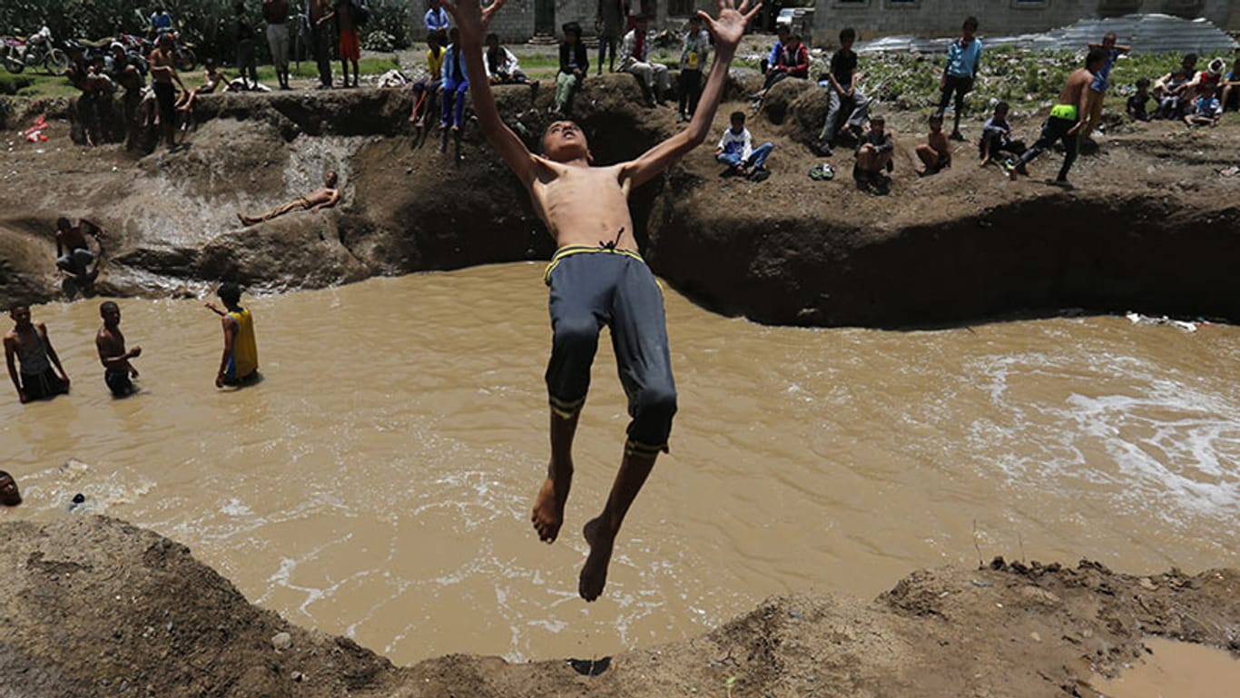 Jugendliche im Jemen machen nach den sintflutartigen Regenfällen das Beste aus der Überflutung.