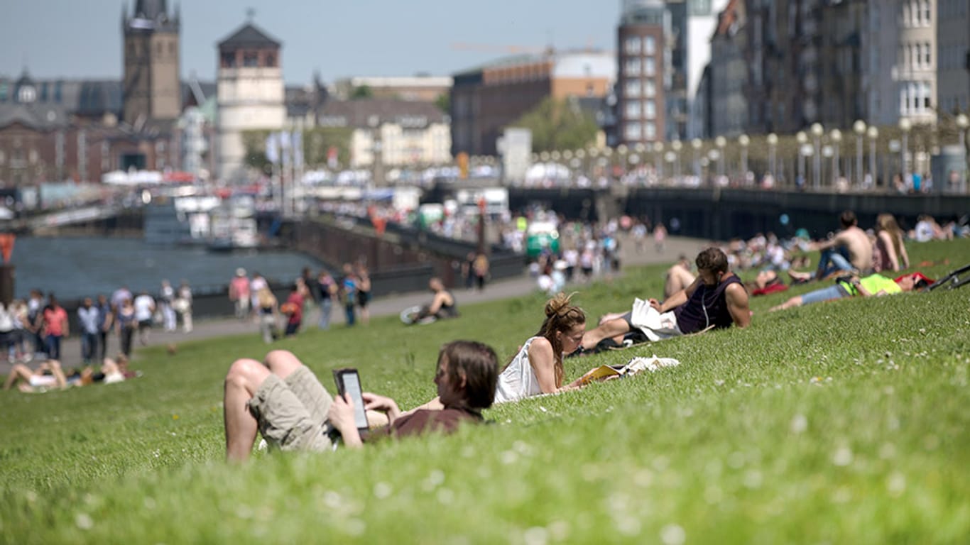 Düsseldorfer entspannen am sonnigen Rheinufer.