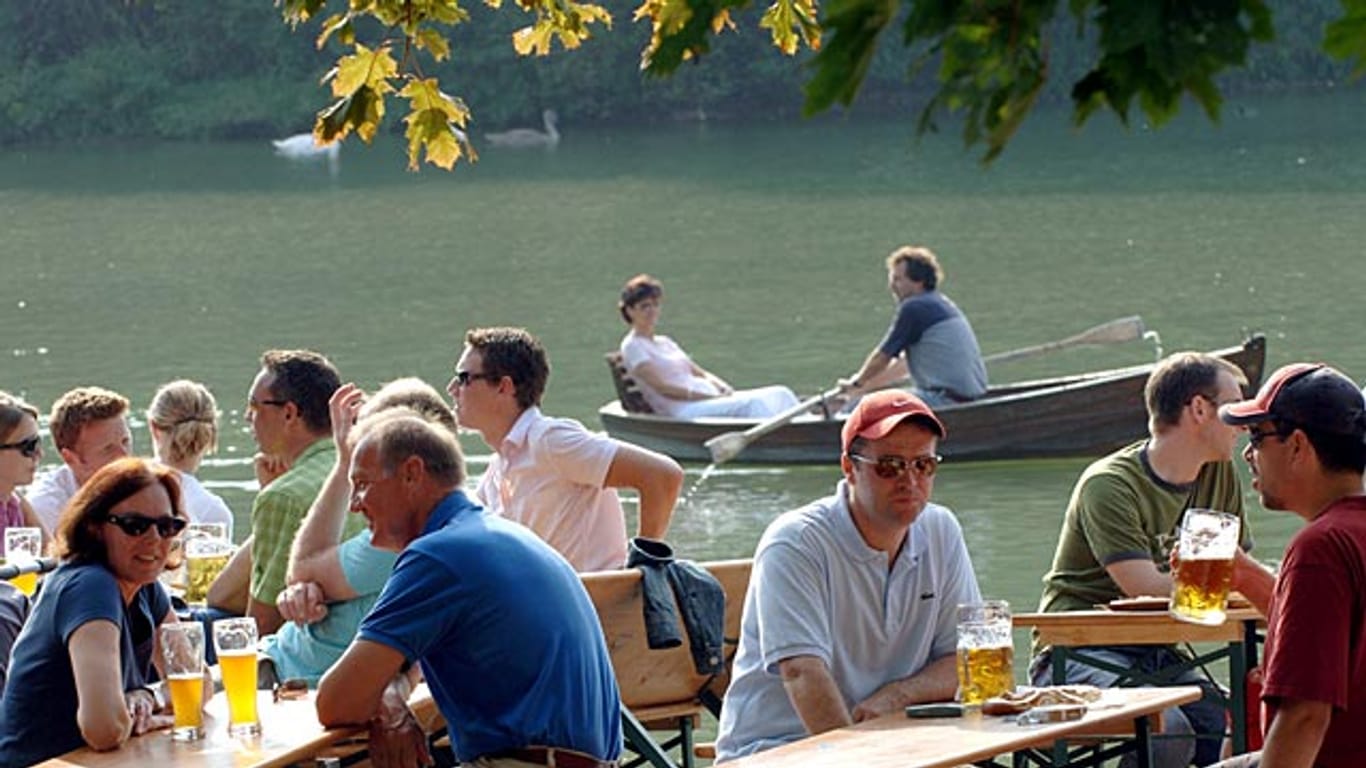 Biergarten-Besucher genießen die Sonne am Kleinhesseloher See im Englischen Garten in München.