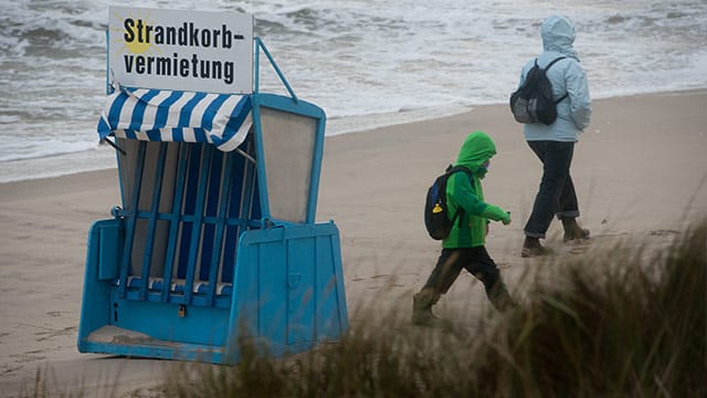 Touristen spazieren am Strand von Zinnowitz auf der Insel Usedom.