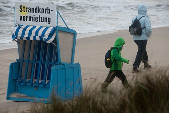 Touristen spazieren am Strand von Zinnowitz auf der Insel Usedom.