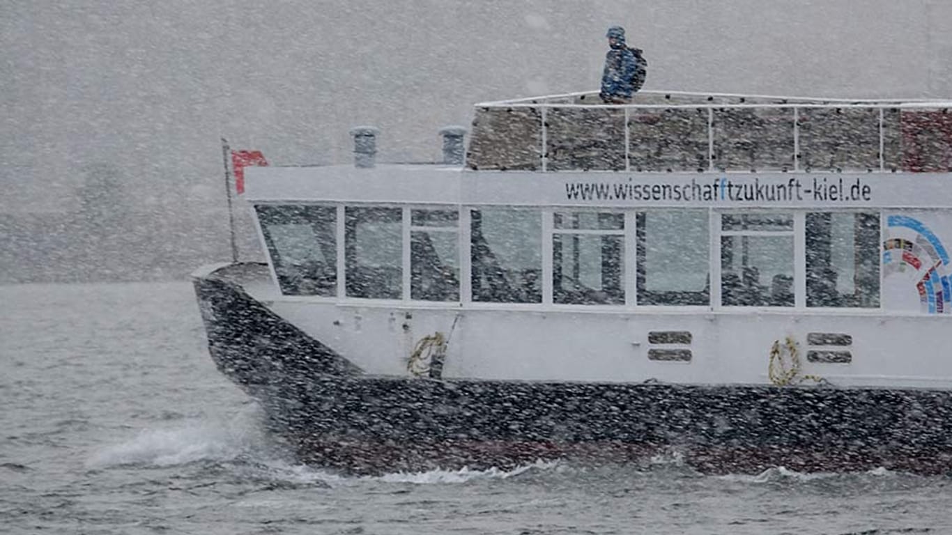 Eine Fähre fährt im Schneetreiben über die Förde in Kiel.