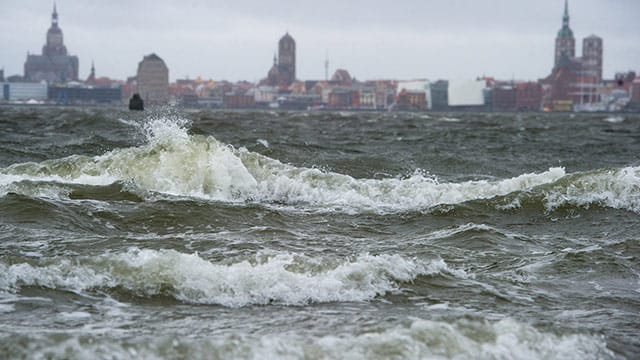 Wellen brechen sich am Strand von Altefähr auf der Insel Rügen. Im Hintergrund ist Stralsund zu sehen. Wellen brechen sich am Strand von Altefähr auf der Insel Rügen. Im Hintergrund ist Stralsund zu sehen.