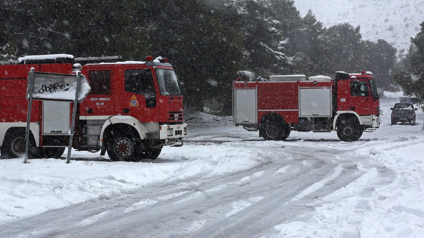 Feuerwehrwagen sind bei heftigem Schneefall in Athen im Einsatz.