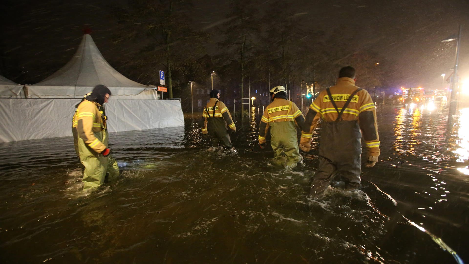 Feuerwehrleute waten durch das Hochwasser der Trave in Lübeck.