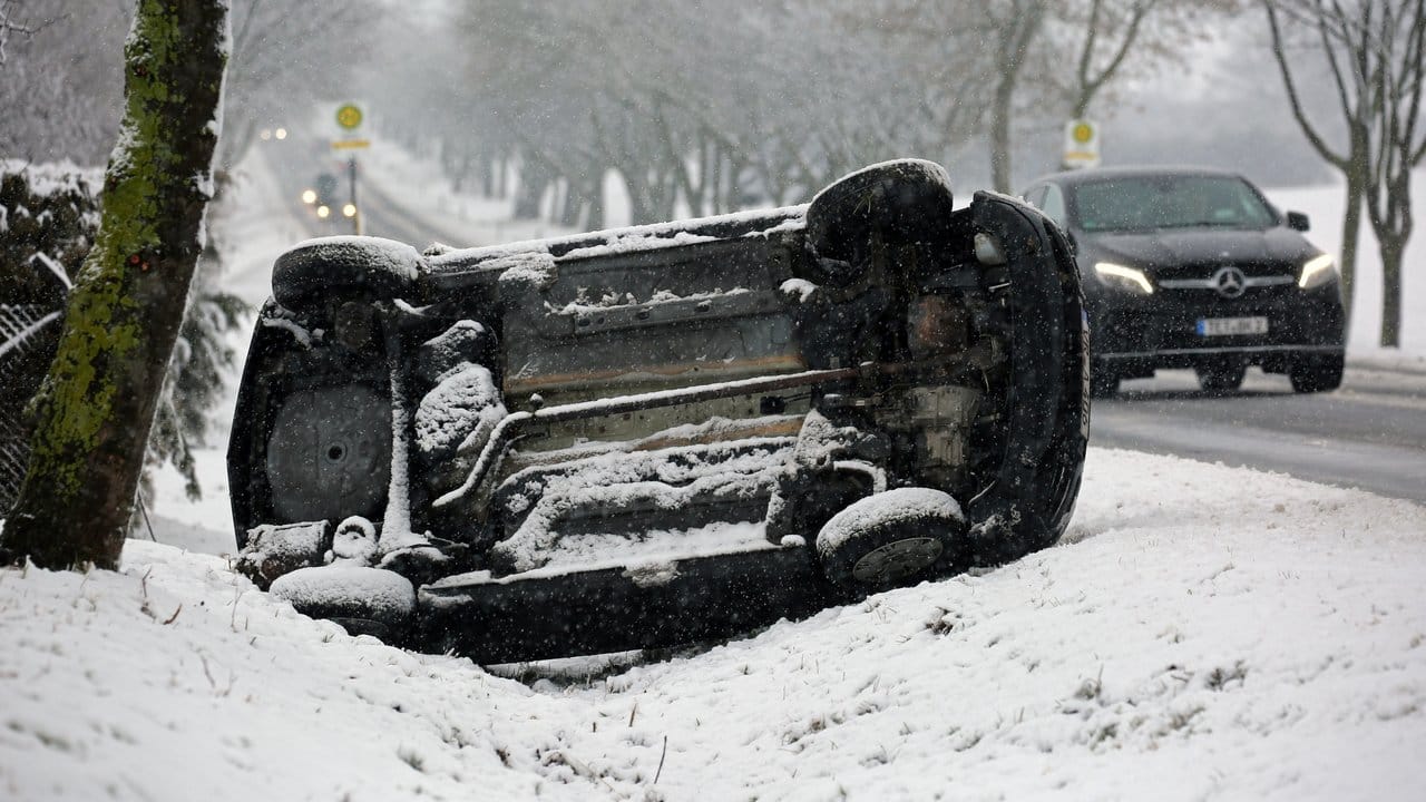 Ein Auto liegt eingeschneit bei Teterow (Mecklenburg-Vorpommern) im Straßengraben.