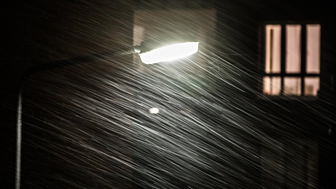 Der Sturm treibt in Frankfurt am Main Schneeflocken an einer Straßenlaterne vorbei.
