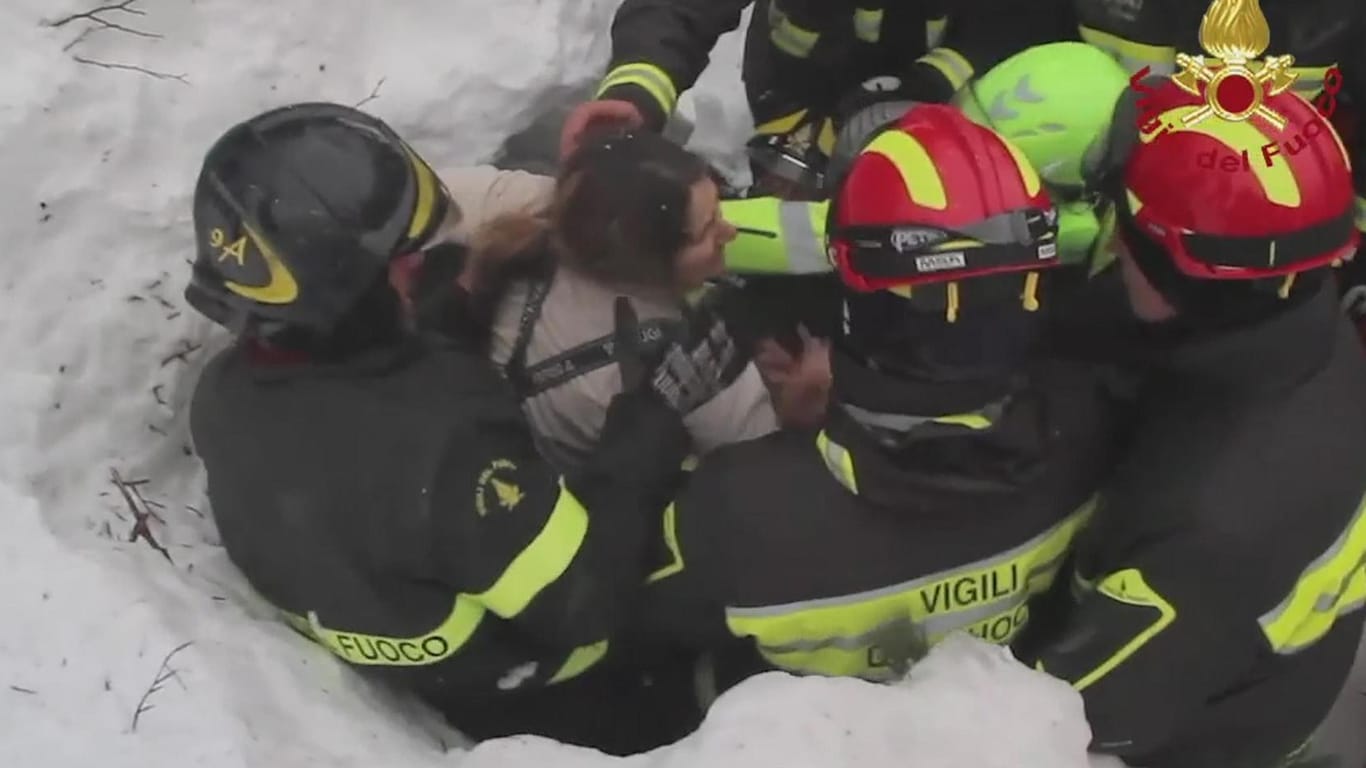 Italienische Rettungskräfte ziehen eine Frau aus den Schneemassen.