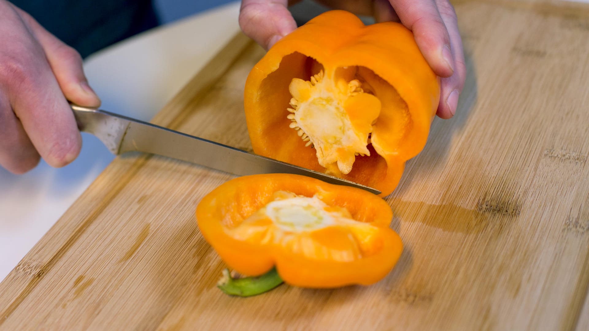 Schritt 1: Die Paprika mit einem Messer rund einen Zentimeter unter dem Stielansatz in zwei Teile schneiden.