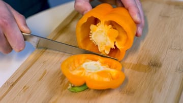 Schritt 1: Die Paprika mit einem Messer rund einen Zentimeter unter dem Stielansatz in zwei Teile schneiden.
