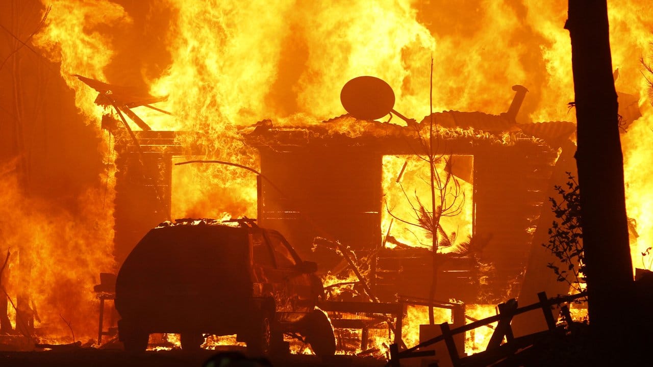 Ein Auto geht während eines Waldbrandes im chilenischen Constitución in Flammen auf. Ein Auto geht während eines Waldbrandes im chilenischen Constitución in Flammen auf.