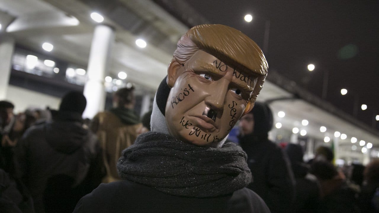 Ein Demonstrant trägt während einer Protestaktion am O'Hare Flughafen in Chicago eine Trump-Maske mit aufgemaltem Hitlerbärtchen.