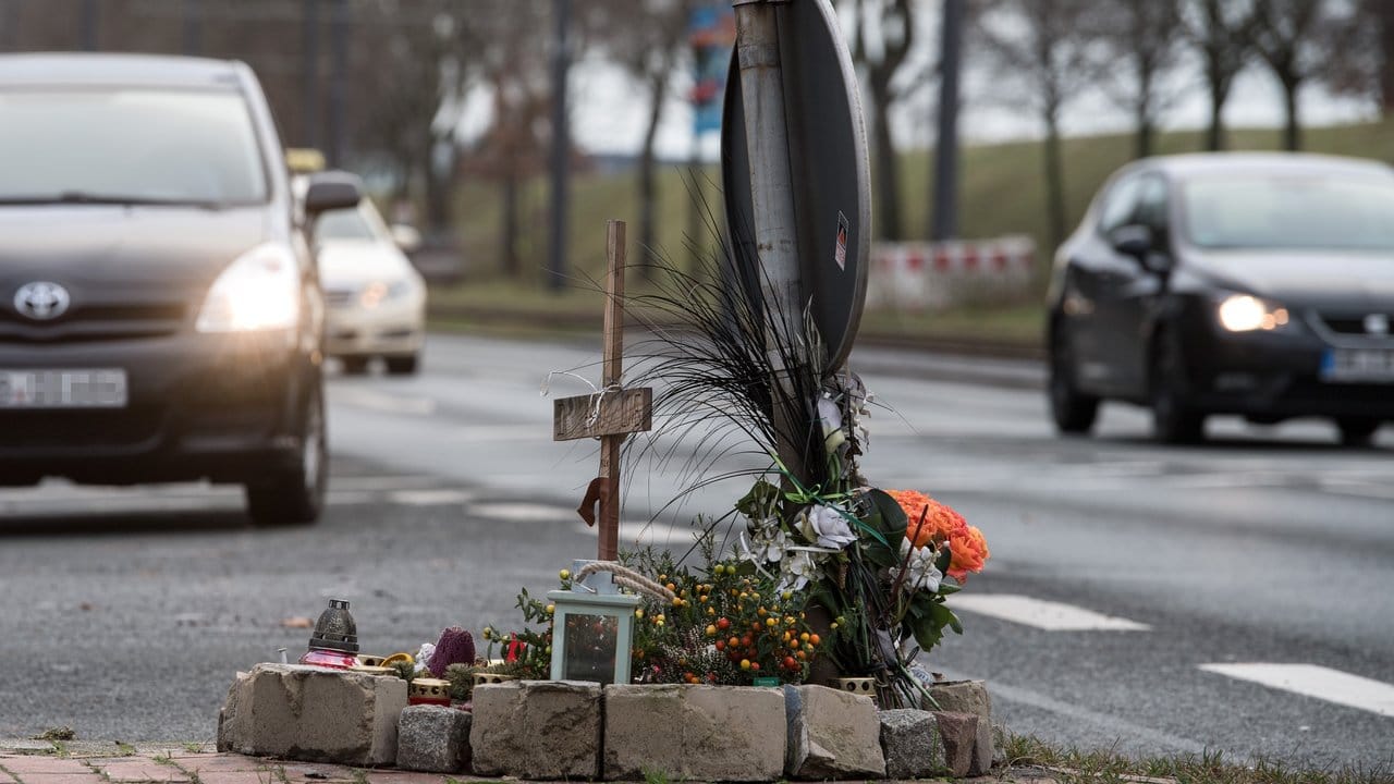 Blumen und ein Holzkreuz erinnern auf einer Kreuzung in Bremen an den Tod des 75 Jahre alten Mannes, der von einem Motorradfahrer überfahren wurde.