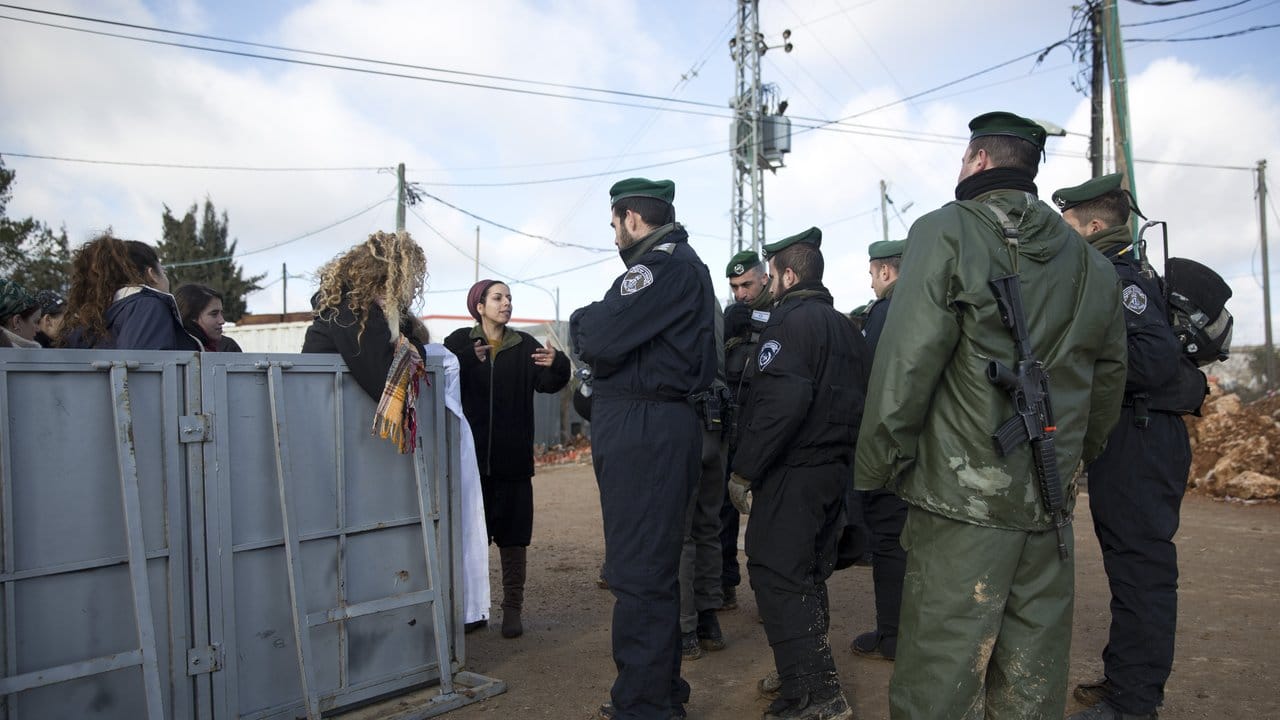 Siedler des israelischen Außenpostens Amona reden mit israelischen Polizisten.