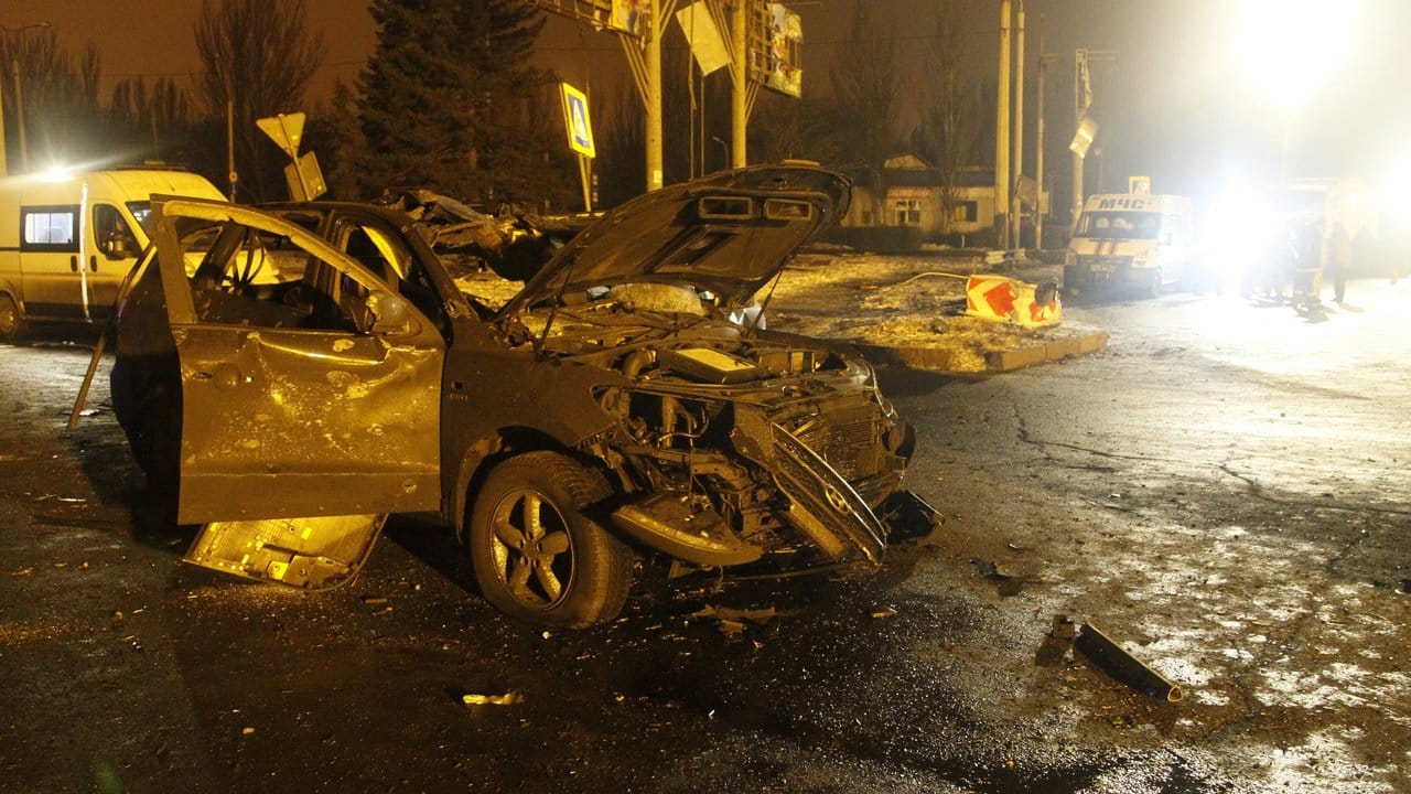 Ein zerstörtes Auto steht in Donezk nach einem Artilleriebeschuss auf der Straße.