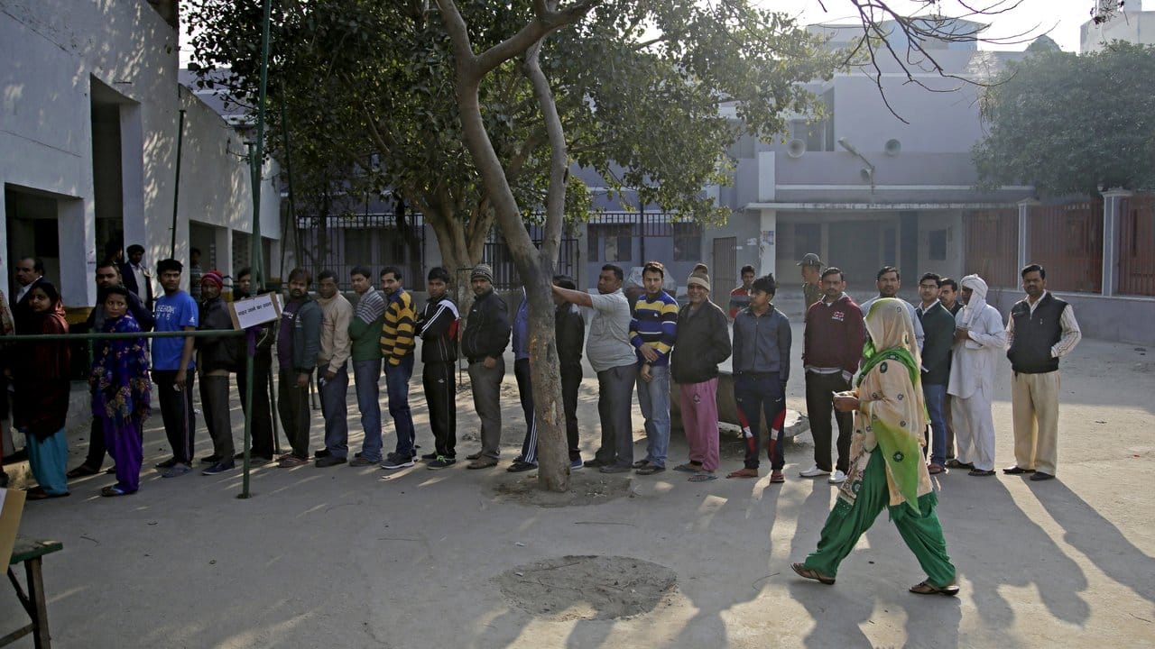 Männer stehen in Bhangel in Uttar Pradesh vor dem örtlichen Wahllokal an.