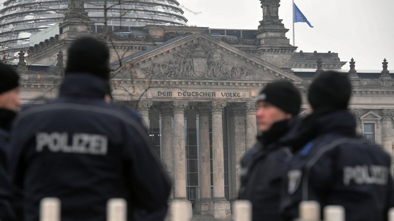 Polizisten an einem Absperrgitter vor der Kulisse des Reichstagsgebäudes in Berlin.