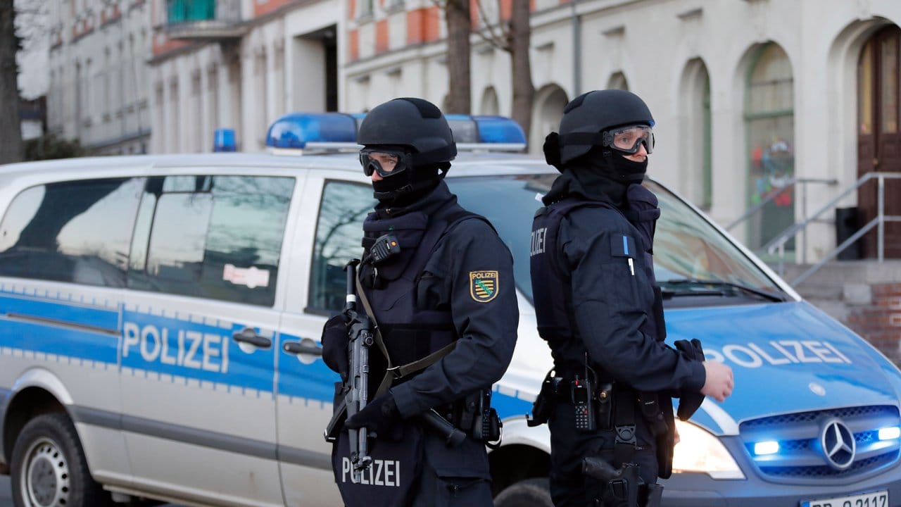 Polizisten stehen vor einem Mehrfamilienhaus in Chemnitz.