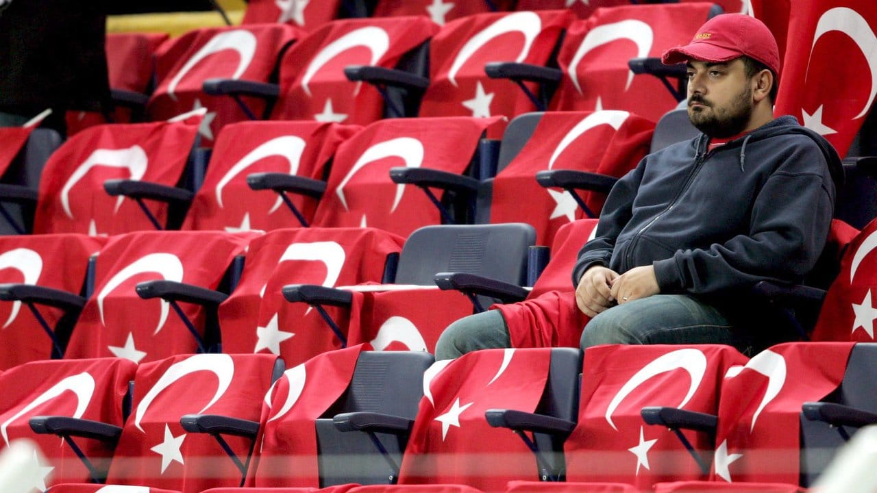 Ein Fußballfan sitzt im Sükrü-Saracoglu-Stadion in Istanbul, dessen Sitze mit türkischen Fahnen geschmückt sind.