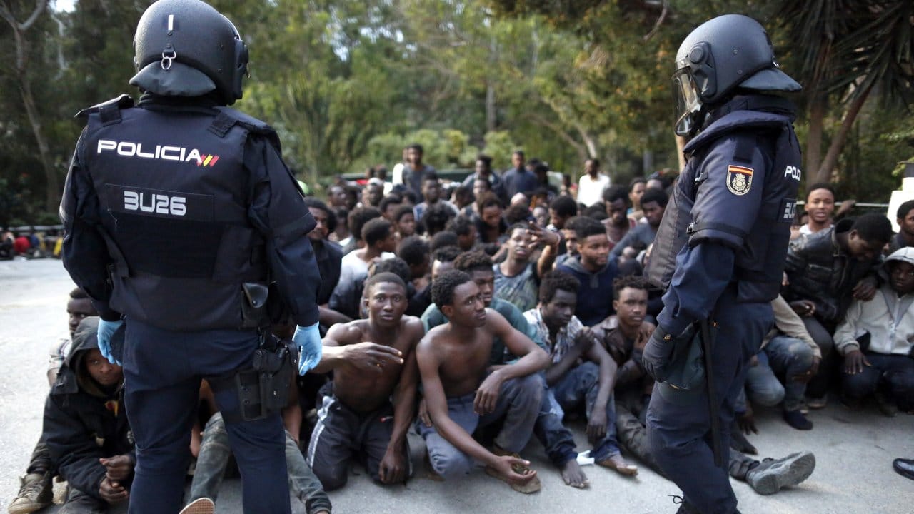 Die Flüchtlinge werden von spanischen Polizisten bewacht.