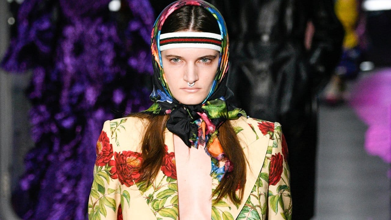 Ein Anzug mit aufgedruckten Blumen, dazu Kopftuch und Stirnband - Gucci demonstriert, was in der Mode alles möglich ist.
