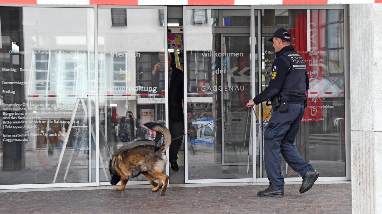Nach der Bombendrohung betritt ein Polizist mit einem Spürhund das Rathaus von Gaggenau.