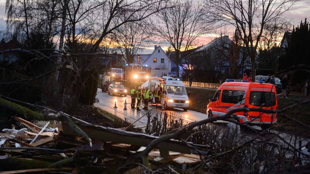 Feuerwehrleute und Anwohner räumen in einem Wohngebiet die Schäden auf. Feuerwehrleute und Anwohner räumen in einem Wohngebiet die Schäden auf.