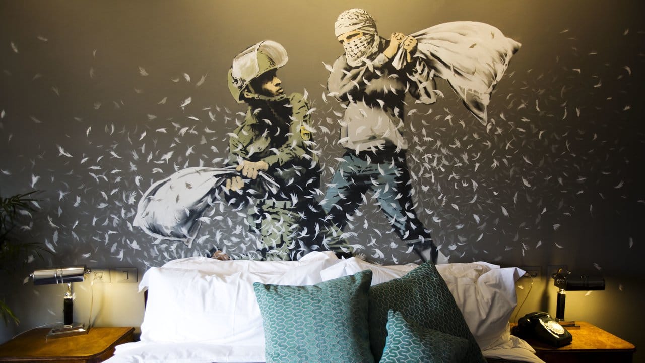 Ein Wandbild von Banksy mit einem israelischen Soldaten und einem Palästinenser bei einer Kissenschlacht im "The Walled Off Hotel" in Bethlehem.