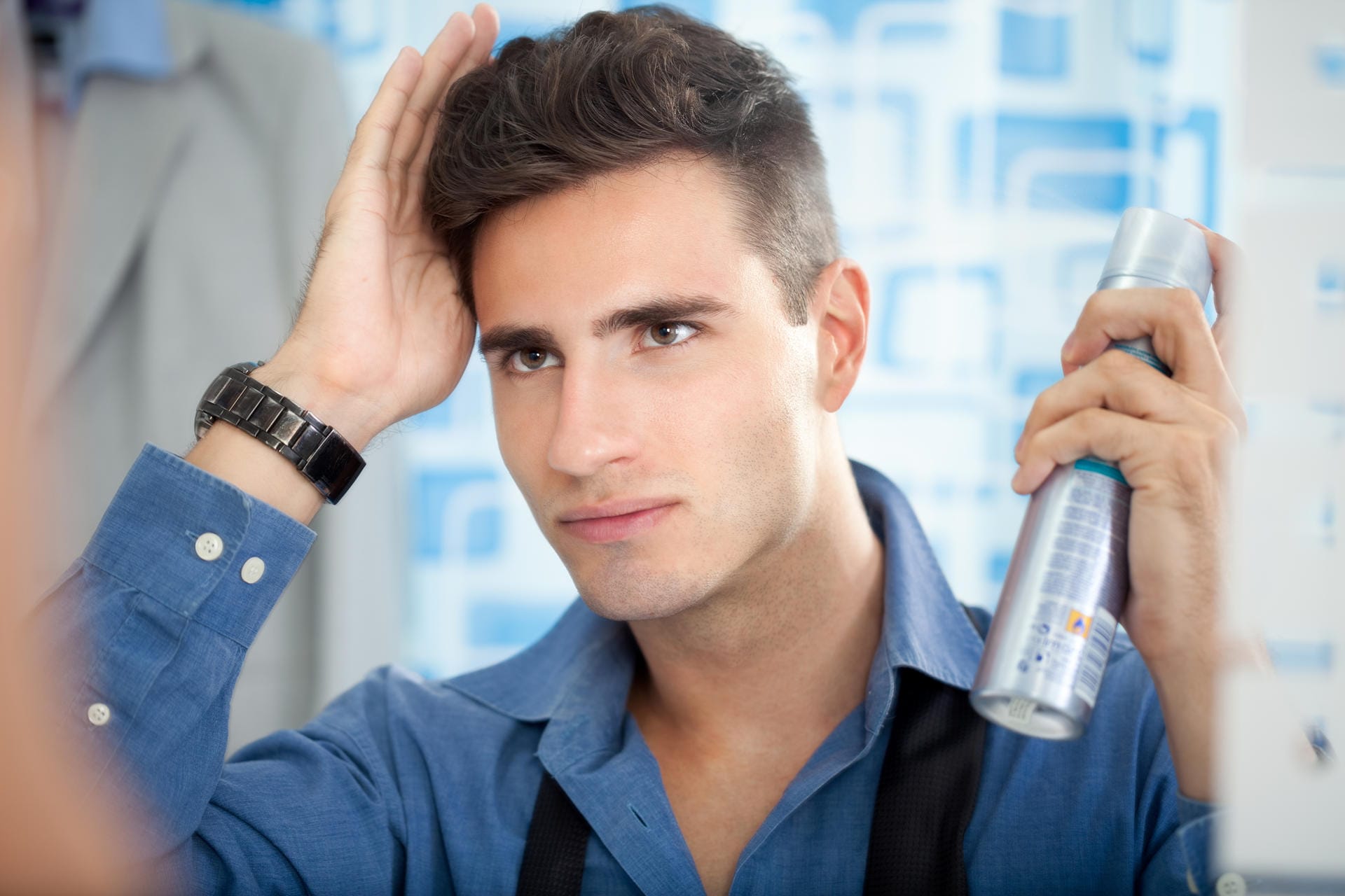 Man styling his hair in the mirror with hairspray