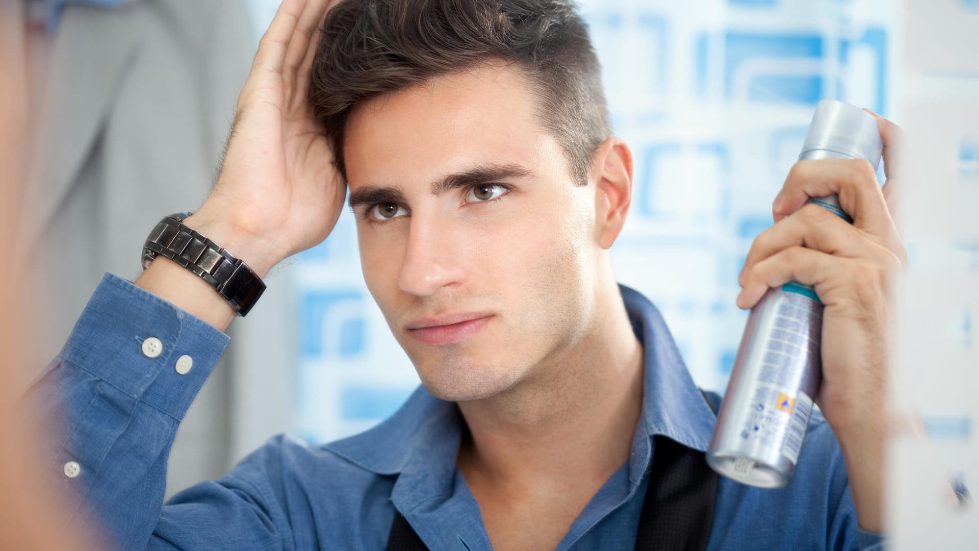 Man styling his hair in the mirror with hairspray