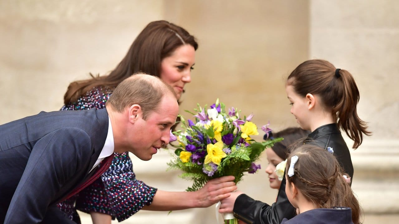 Prinz William und seine Frau, die Herzogin von Cambridge bekommen von kleinen Mädchen Blumen überreicht.