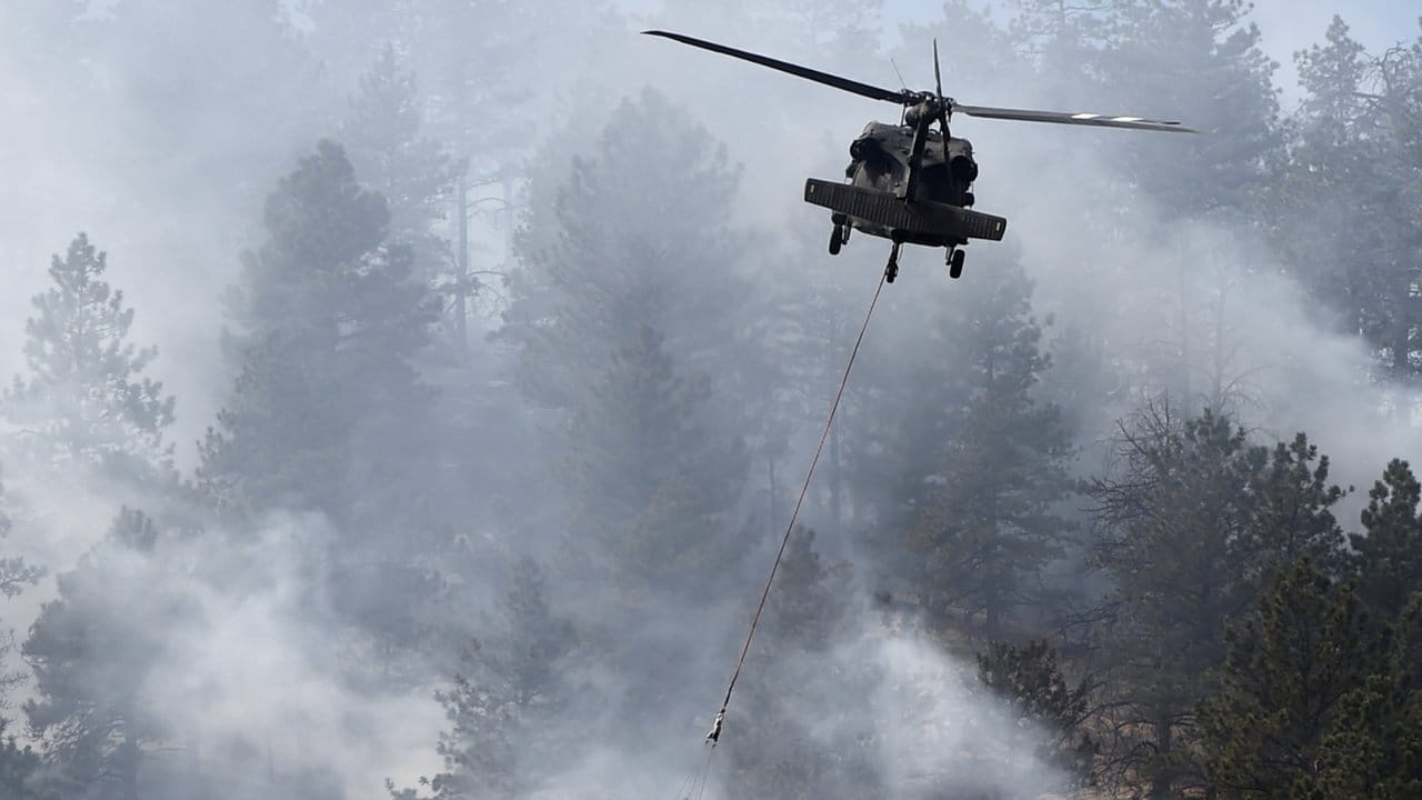 Ein Helikopter löscht in Boulder, Colorado (USA) einen Waldbrand mit einem Wassersack.