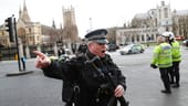 Wegweiser: Ein bewaffneter Beamter gibt Anweisungen, wie sich die Leute nach den Angriffen in London verhalten sollen.