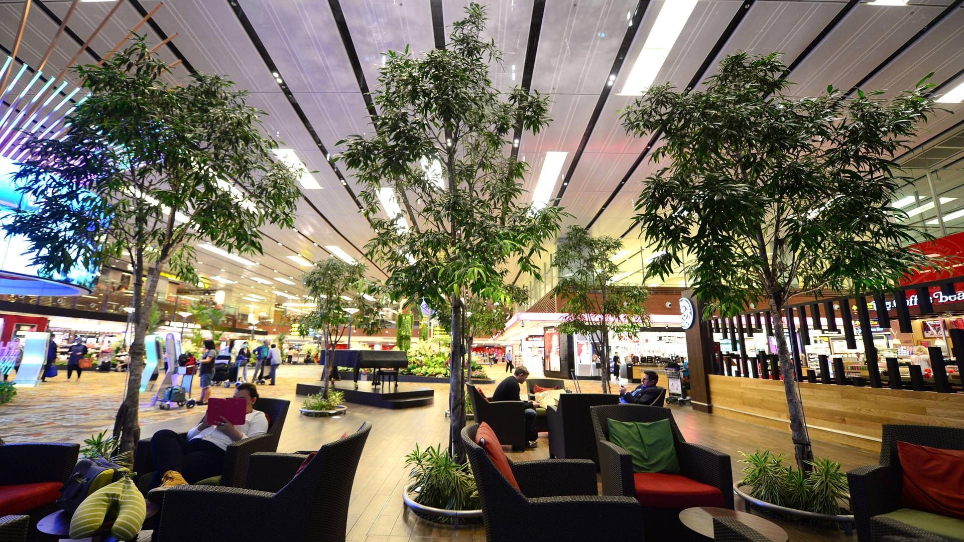 Passagiere entspannen im begrünten Wartebereich von Changi International Airport in Singapore