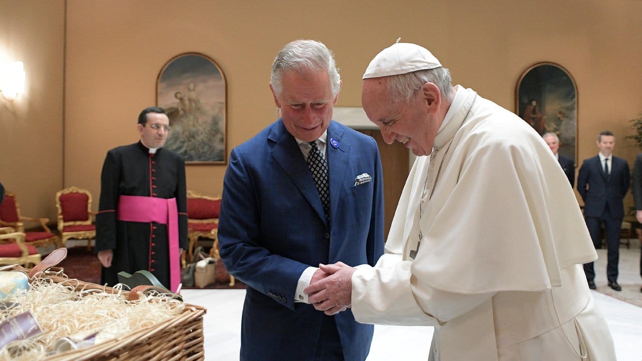 Papst Franziskus (r) schüttelt Prinz Charlesdie Hand.