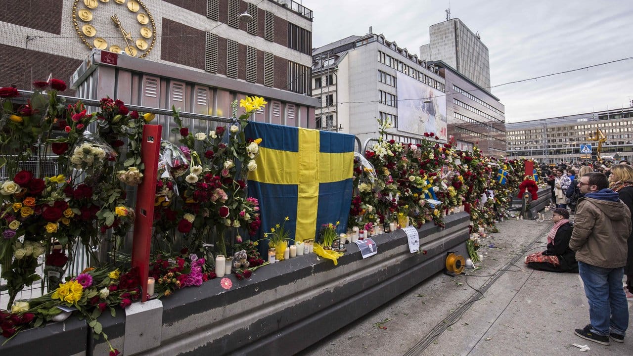 Passanten haben Blumen an einer Absperrung vor dem Stockholmer Kaufhaus Åhléns City befestigt. Passanten haben Blumen an einer Absperrung vor dem Stockholmer Kaufhaus Åhléns City befestigt.