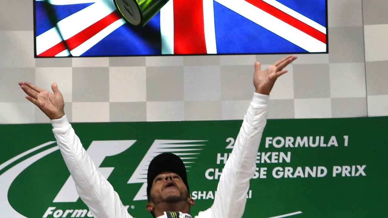 Shanghai-Sieger Lewis Hamilton wirft seine Trophäe in die Luft.