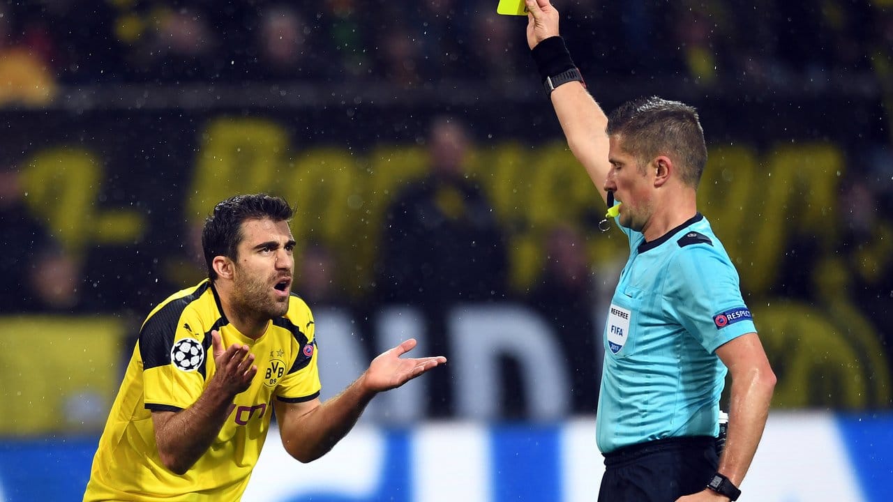 Schiedsrichter Nicola Rizzoli aus Italien zeigt dem Dortmunder Sokratis Papastathopoulos (l) die gelbe Karte.