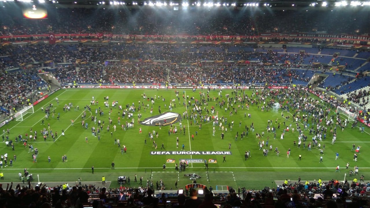 Ajax-Fans flüchten sich vor Feuerwerkskörpern auf das Spielfeld.