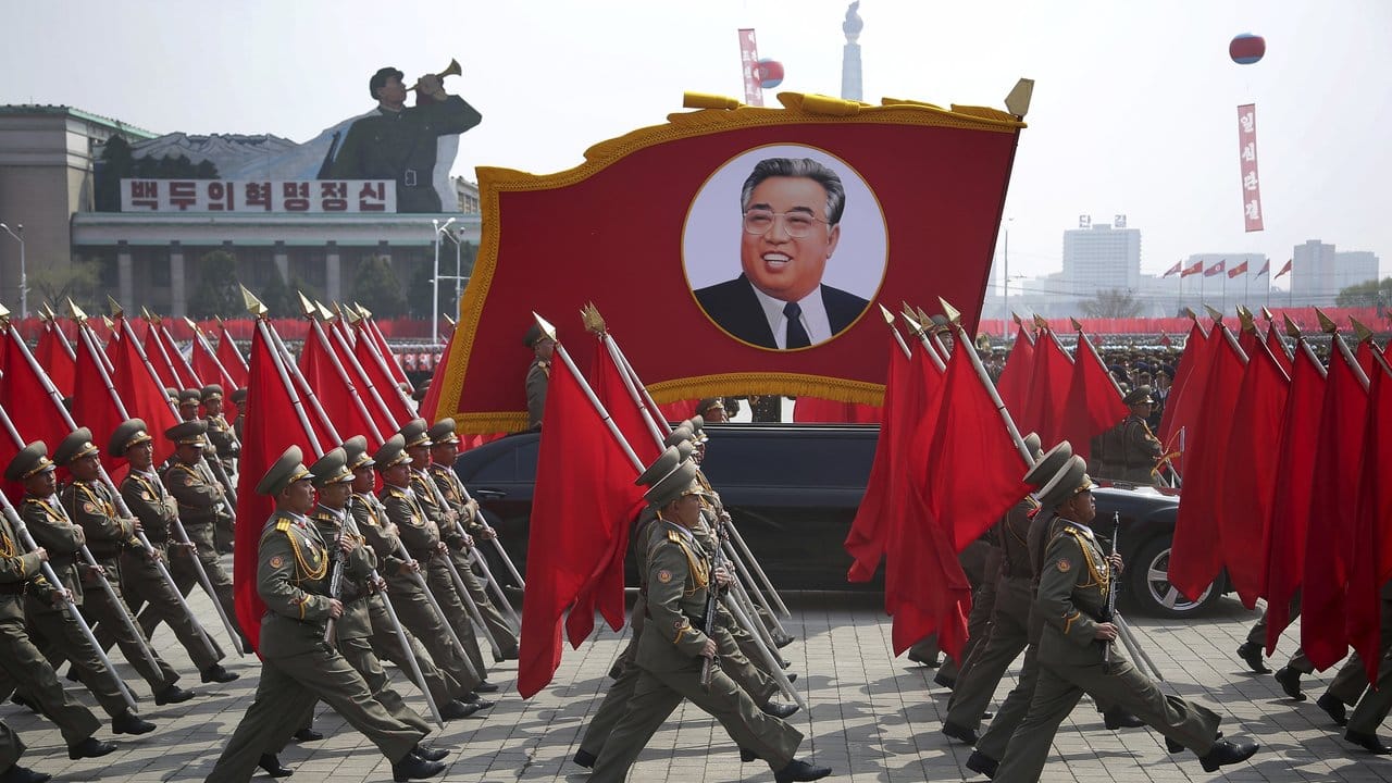 Nordkoreanische Soldaten tragen Flaggen und ein Foto von Kim Il Sung bei der Militärparade in Pjöngjang. Nordkoreanische Soldaten tragen Flaggen und ein Foto von Kim Il Sung bei der Militärparade in Pjöngjang.