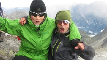 Zwei Jugendliche am Gipfel bei der Alpenüberquerung.