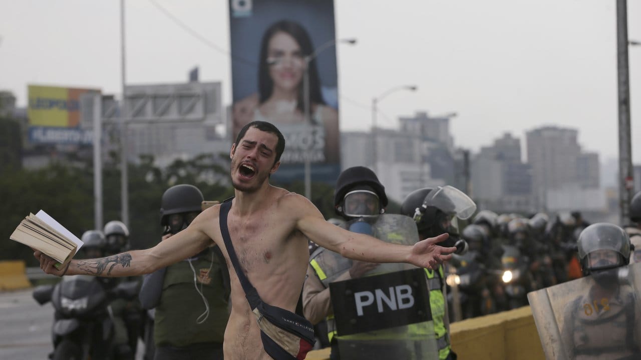 Ein nackter Demonstrant hält während eines Protests gegen die Regierung eine Bibel hoch.