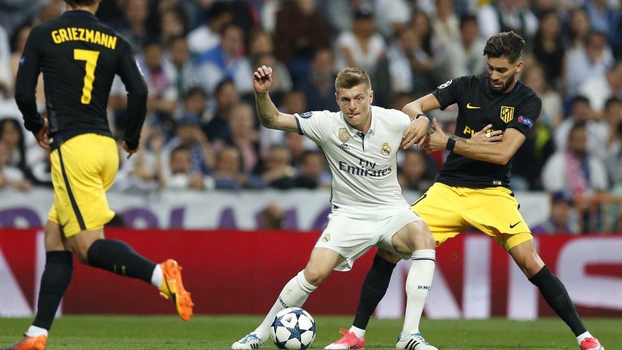 Real Madrids Toni Kroos (M) behauptet sich im Zweikampf um den Ball gegen Yannick Carrasco (r) von Atlético Madrid.