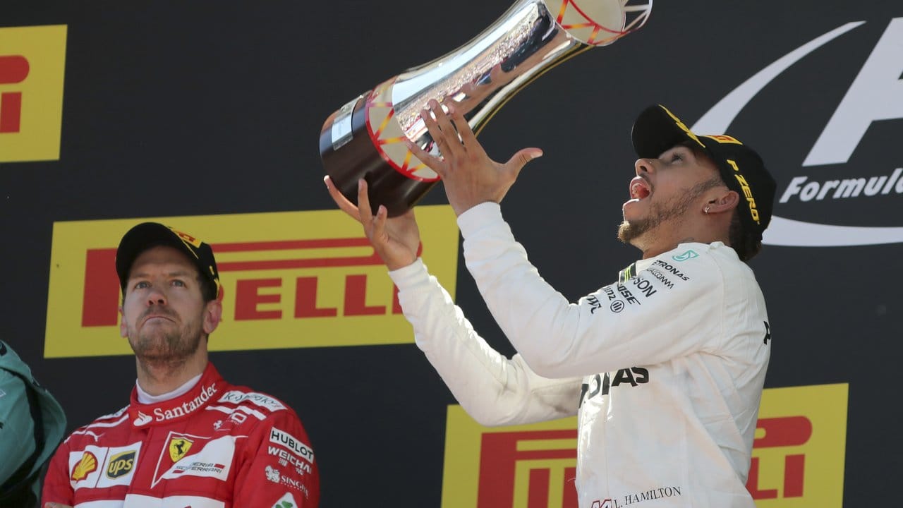 Lewis Hamilton jubelt über seinen Sieg, Sebastian Vettel (l) applaudiert mit ernster Miene.